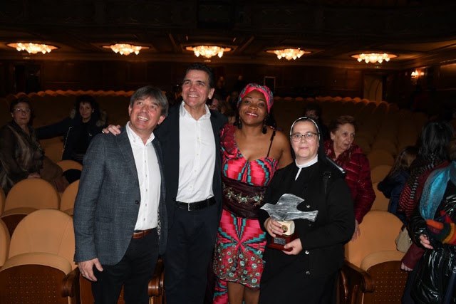La superiora de la casa sostiene el premio en el patio de butacas del teatro Jovellanos, acompañada por la soprano Cinthya Zebaze y dos asistentes al acto